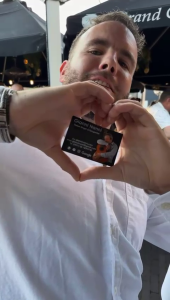 Een fan maakt een hartgebaar met het visitekaartje van de Italiaanse zanger Gianni Nanni tijdens een evenement.